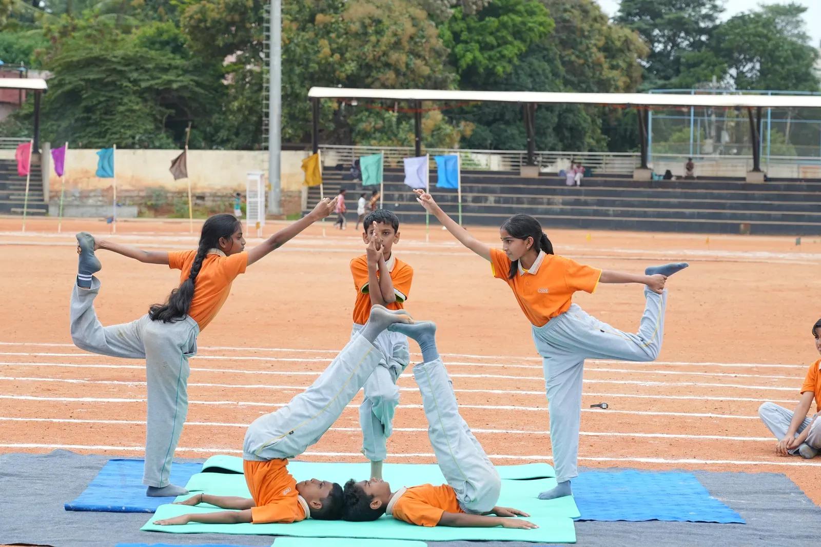 Students performing a partner yoga asana on the school ground